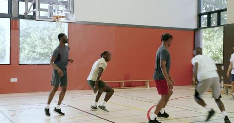 African american men playing indoor basketball showing teamwork, athleticism and fitness