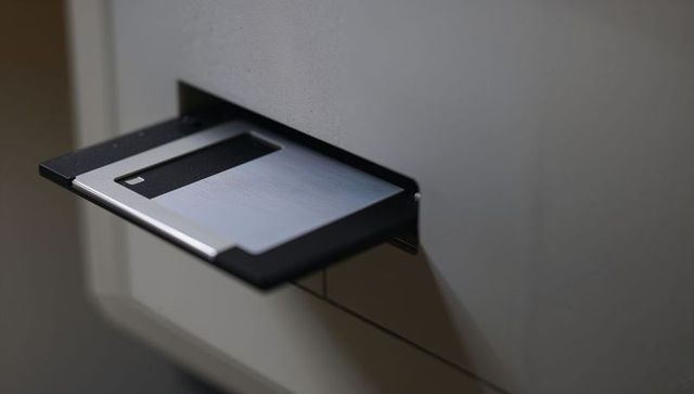 Inserting 3.5-inch floppy disk into beige drive slot retro vintage closeup computer