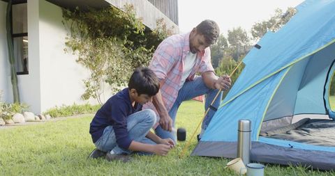 Father and Son Setting Up Tent in Backyard for Camping Adventure
