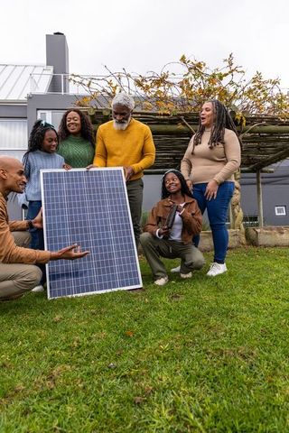 Multigenerational african american family learning about solar panel in backyard for renewable energ