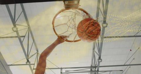 Basketball Player Skillfully Dunking Ball Into Hoop