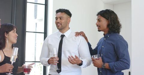 Diverse friends chatting and celebrating indoors with drinks formal casual attire