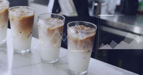 Iced lattes layering on marble counter with futuristic analytics overlay and glassware ui