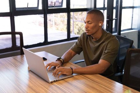 African american man working on laptop in modern coworking space, focused on productivity