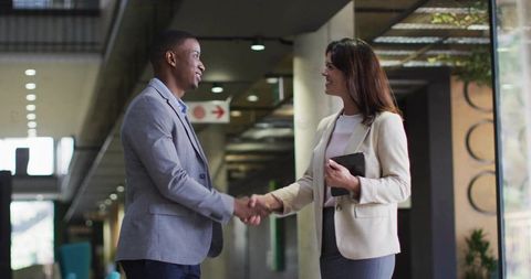 Two Business Professionals Shaking Hands in Office Corridor