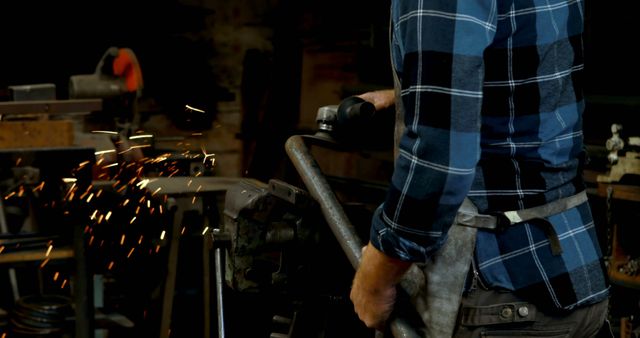 Man using a grinder on metal producing bright sparks in a workshop. Useful for illustrations on metalworking, craftsmanship, safety in industrial environments, and blue-collar occupations.