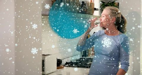 Woman drinking water in cozy minimalist kitchen with winter snowflake overlay teal accents