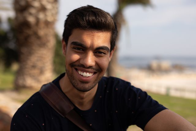 Portrait close up of a biracial man enjoying free time in nature on a sunny day, looking to a camera and smiling.