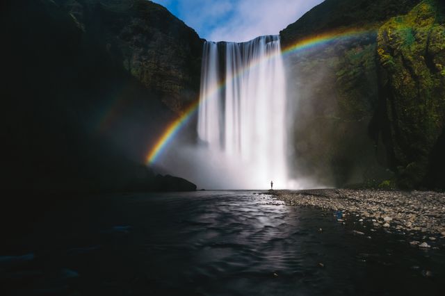 Lone Traveler Looking at Majestic Waterfall with Rainbow - Download Free Stock Photos Pikwizard.com