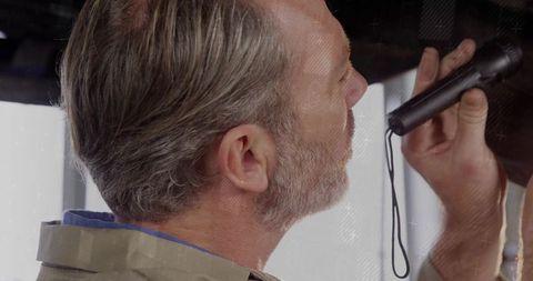Senior Man Speaking into Handheld Microphone Holding Recorder Near Window Profile