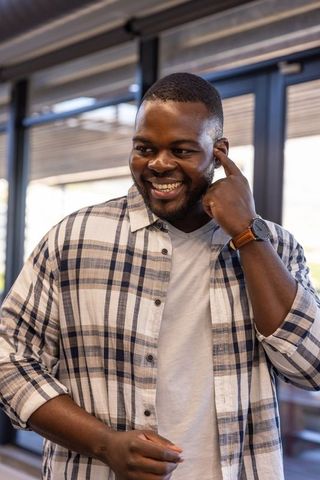 Smiling Professional Touching Ear in Modern Office
