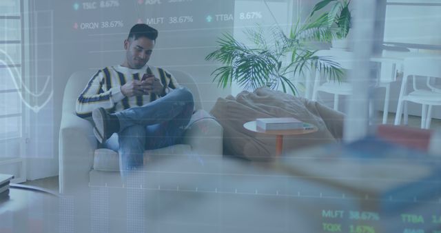 Man casually sitting on armchair using smartphone in modern living room with financial charts overlay. Useful for themes like finance, technology, home office, multitasking, and modern lifestyle.