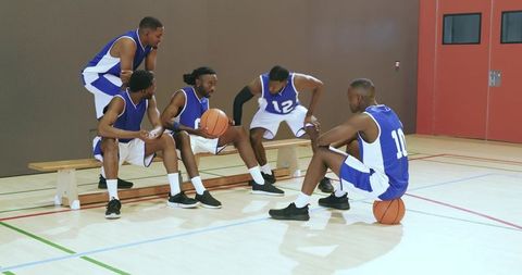African american basketball team huddling on bench planning strategy during timeout