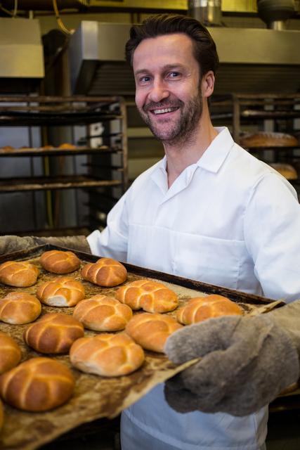 Portrait of smiling baker holding a tray of freshly baked buns