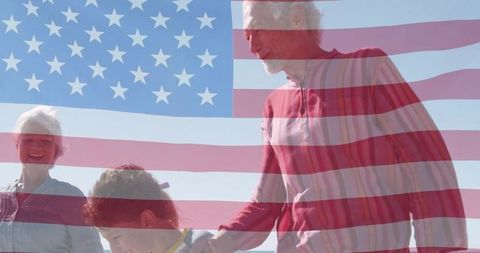 Grandparents and child holding hands at beach with american flag overlay celebrating unity