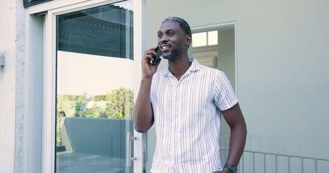 Confident Man Relaxing on Balcony While Chatting on Smartphone