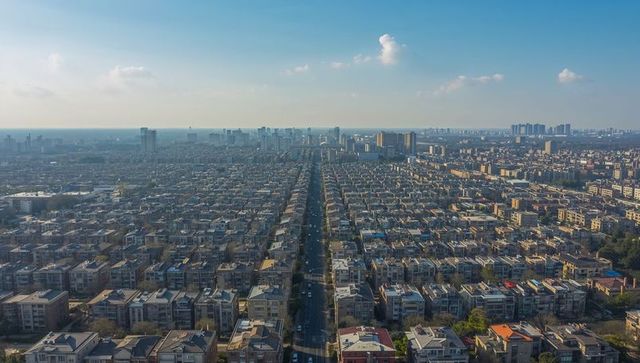 Aerial grid of residential rooftops stretching along central boulevard during golden hour