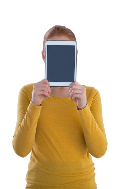 Businesswoman holding digital tablet in front of face while standing against white background
