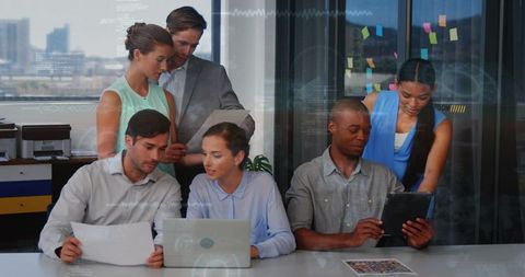Multiracial Team Collaborating Over Laptop and Tablet in Modern Office