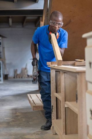 African american carpenter working with hand plane in woodworking workshop