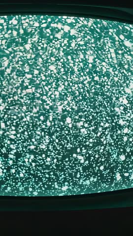 Zooming into green CRT static with visible scanlines, vertical vintage analog TV footage