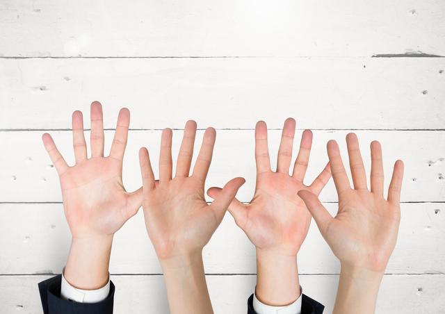 Digital composite of Many hands reaching against white wall