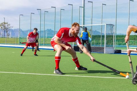 Competitive field hockey match tensions rise as player strikes ball