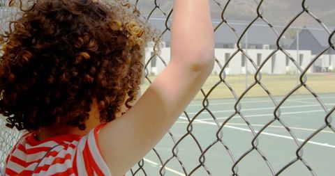 Boy with Curly Hair Looking Through Fence On Sunny Day - Download Free Stock Images Pikwizard.com