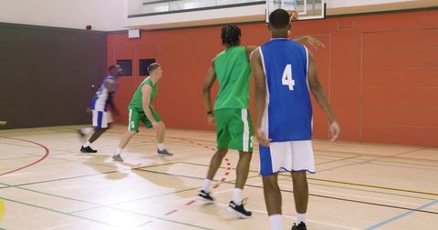African american basketball player #4 dribbling and passing on indoor court
