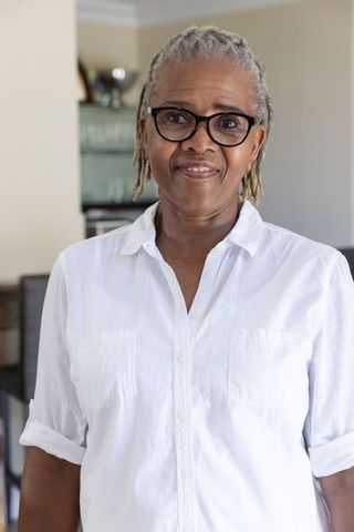 Senior african american woman smiling in white collared shirt and glasses, home portrait