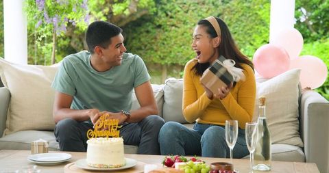 Happy couple celebrating birthday with gifts and cake