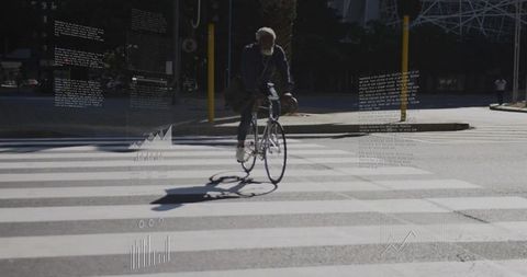Cyclist riding across sunlit zebra crossing casting long shadow on urban street during sunny day