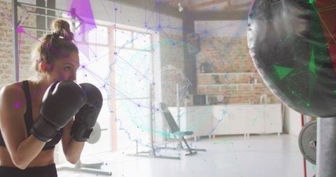 Woman boxing in industrial gym with heavy bag and digital network overlay, neon tech