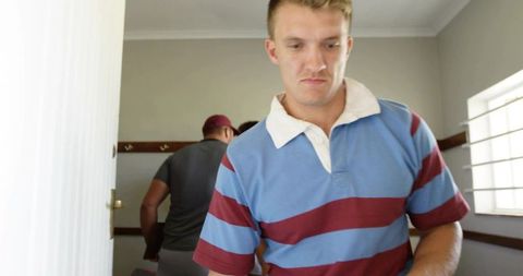 Male Athlete Adjusting Sports Gear in Locker Room Preparing for Team Game or Practice