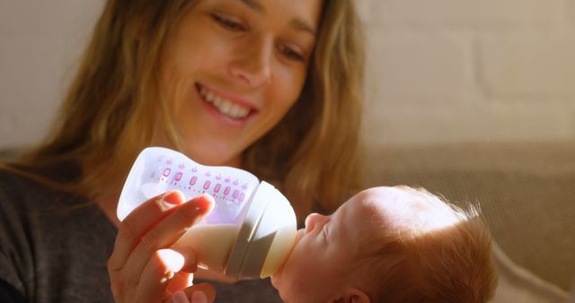 Smiling Mother Feeding Baby with Bottle at Home - Download Free Stock Images Pikwizard.com