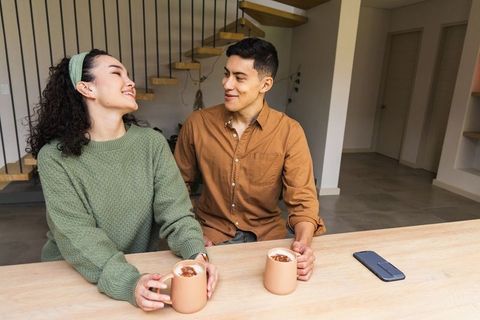 Couple sharing morning coffee at modern kitchen island with minimalist staircase
