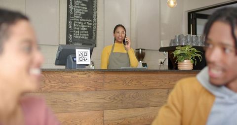 Barista taking phone order behind counter with qr code display and warm café interior