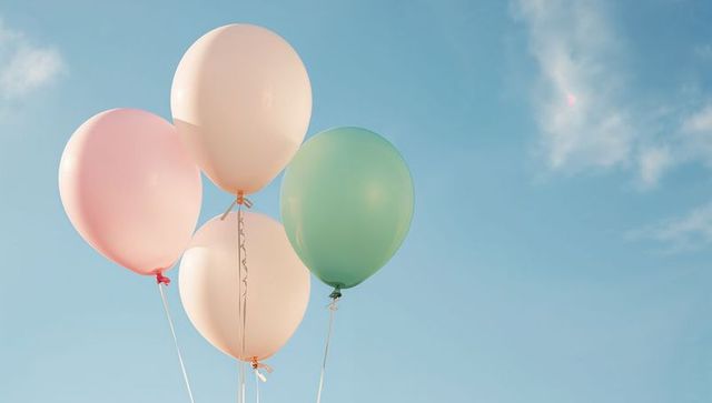 Pastel helium balloons floating against clear blue sky minimalist celebration background