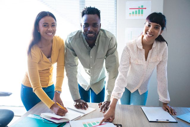 This image is ideal for illustrating concepts of teamwork, collaboration, and diversity in a corporate setting. It can be used in business presentations, company websites, and marketing materials to highlight a positive and inclusive work environment. The smiling faces and engaged posture of the coworkers suggest a productive and harmonious team dynamic.