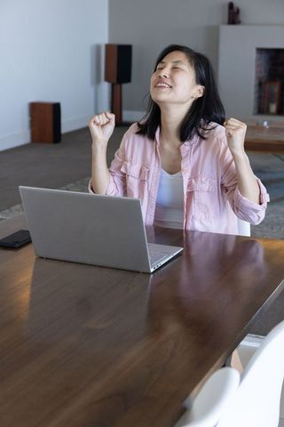Woman Celebrating Success Working on Laptop in Modern Living Room