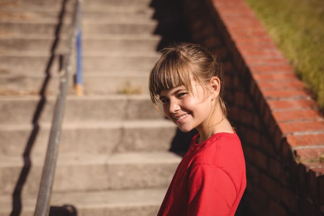 Portrait of happy girl standing near staircase during obstacle course in boot camp