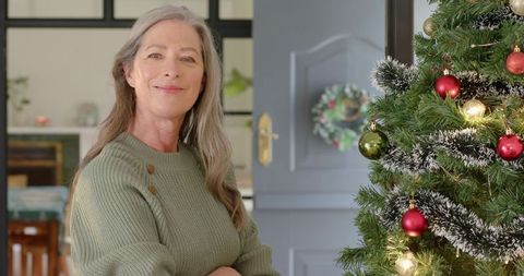 Senior Woman Celebrating Christmas by Decorated Tree at Home