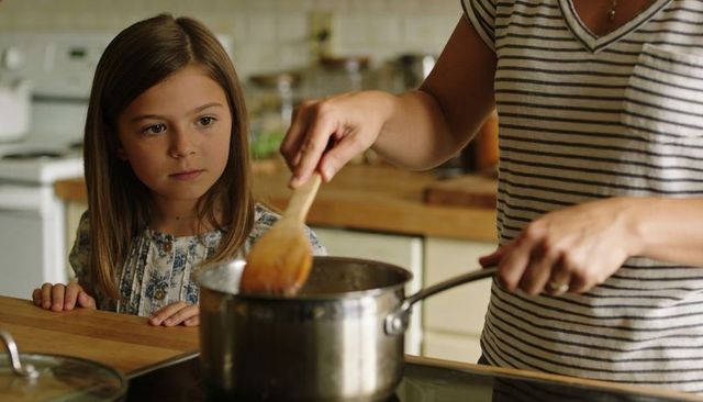 Parent and child cooking together stirring pot and bonding in warm home kitchen moment
