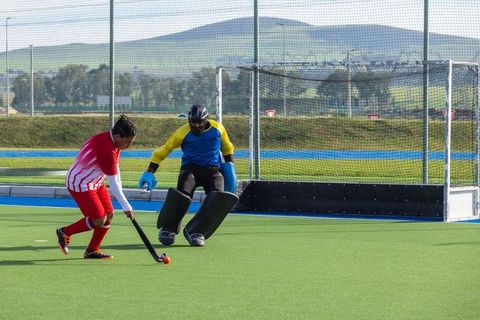 Athlete Dribbling Hockey Ball Towards Goalkeeper on Field