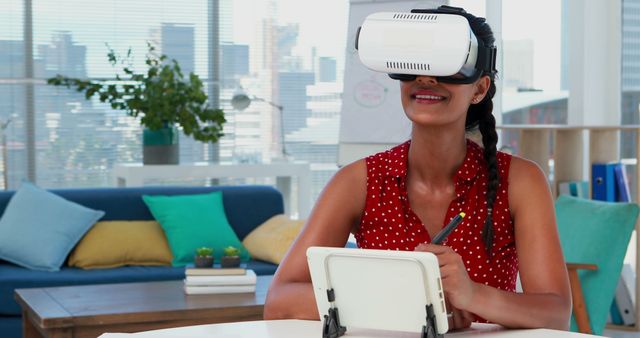 Woman experiencing virtual reality while interacting with tablet in modern, bright office. Useful for illustrating themes of technology adoption, innovative workspaces, digital transformation, and modern business environments.