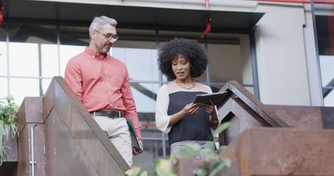 Colleagues Collaborating on Tablet in Modern Office Stairway