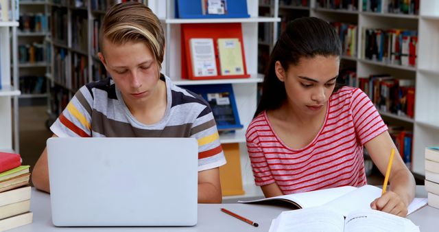 Teenagers studying together at library table with laptop and books - Download Free Stock Images Pikwizard.com