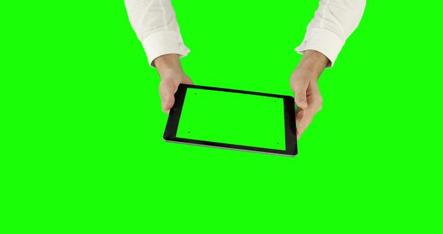 Hands wearing white shirt are holding a tablet with a green screen, suitable for customization and display purposes. Green screen enables easy content overlay for presentations or marketing materials. Useful for tech tutorials, advertisements, or software demonstrations.