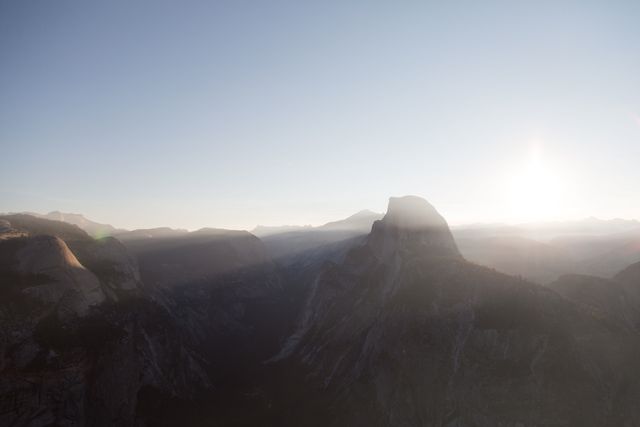 Scenic sunrise over Half Dome in Yosemite National Park, showcasing misty valleys and rugged mountain terrain. Ideal for travel promotions, outdoor adventure themes, and inspirational nature shots.