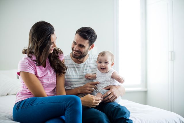 Couple with playing with baby girl in bedroom at home